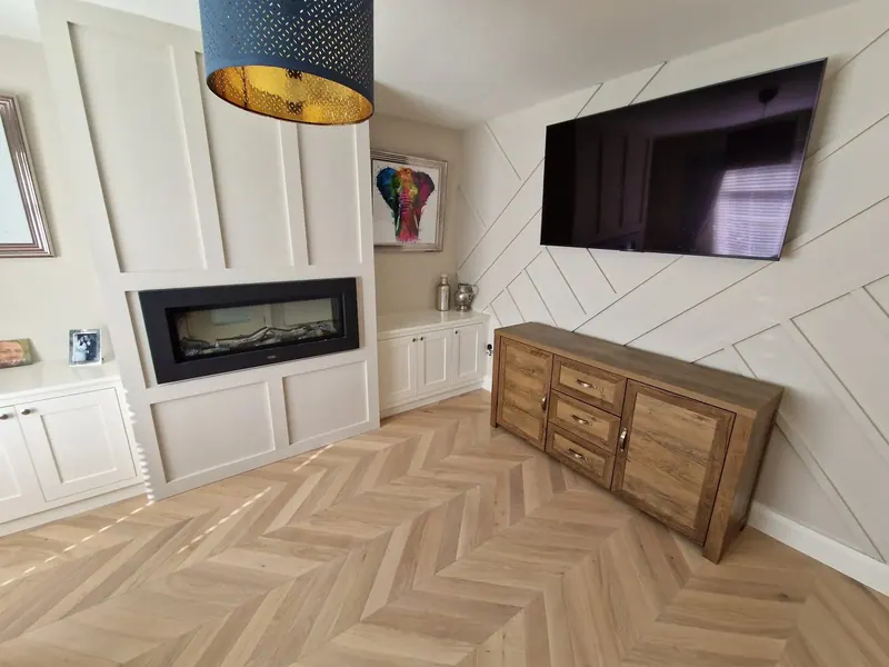 Bespoke fitted media wall and alcove cabinets in a living room with herringbone floor