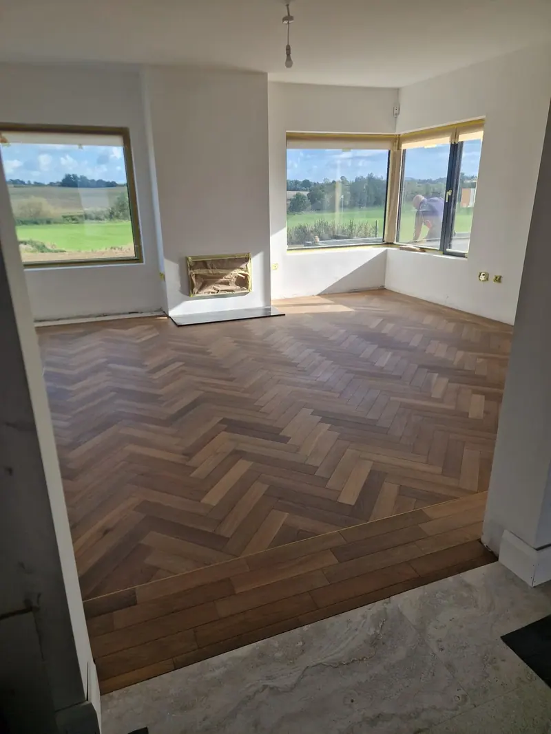 Deep-toned herringbone in a bay window living room with a fireplace
