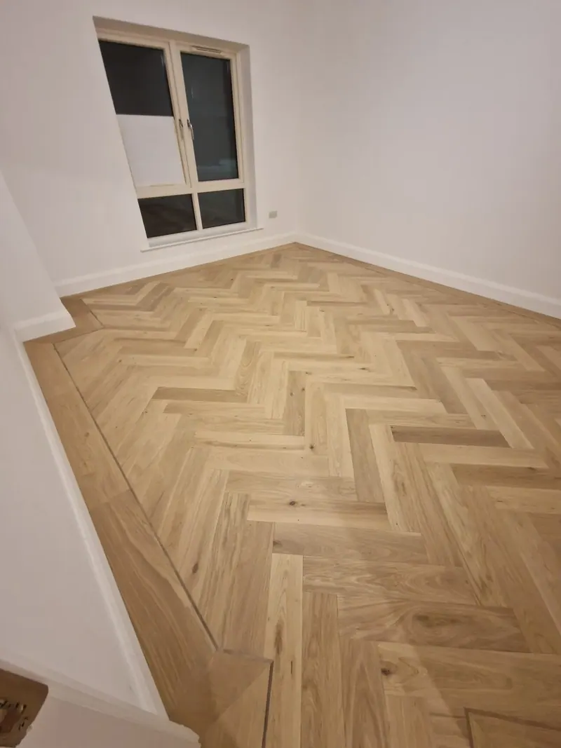 Pale herringbone floor in a bright, freshly decorated room