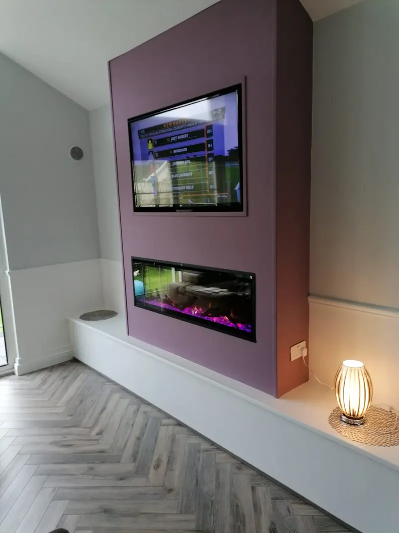 Grey herringbone floor in a living room with a fireplace media wall